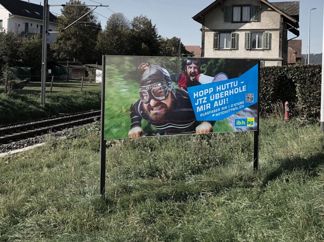 Plakatkampagne der ibh ag zum Glasfaserausbau in Huttwil, Aushang mit Kampagnensujet und QR-Code.