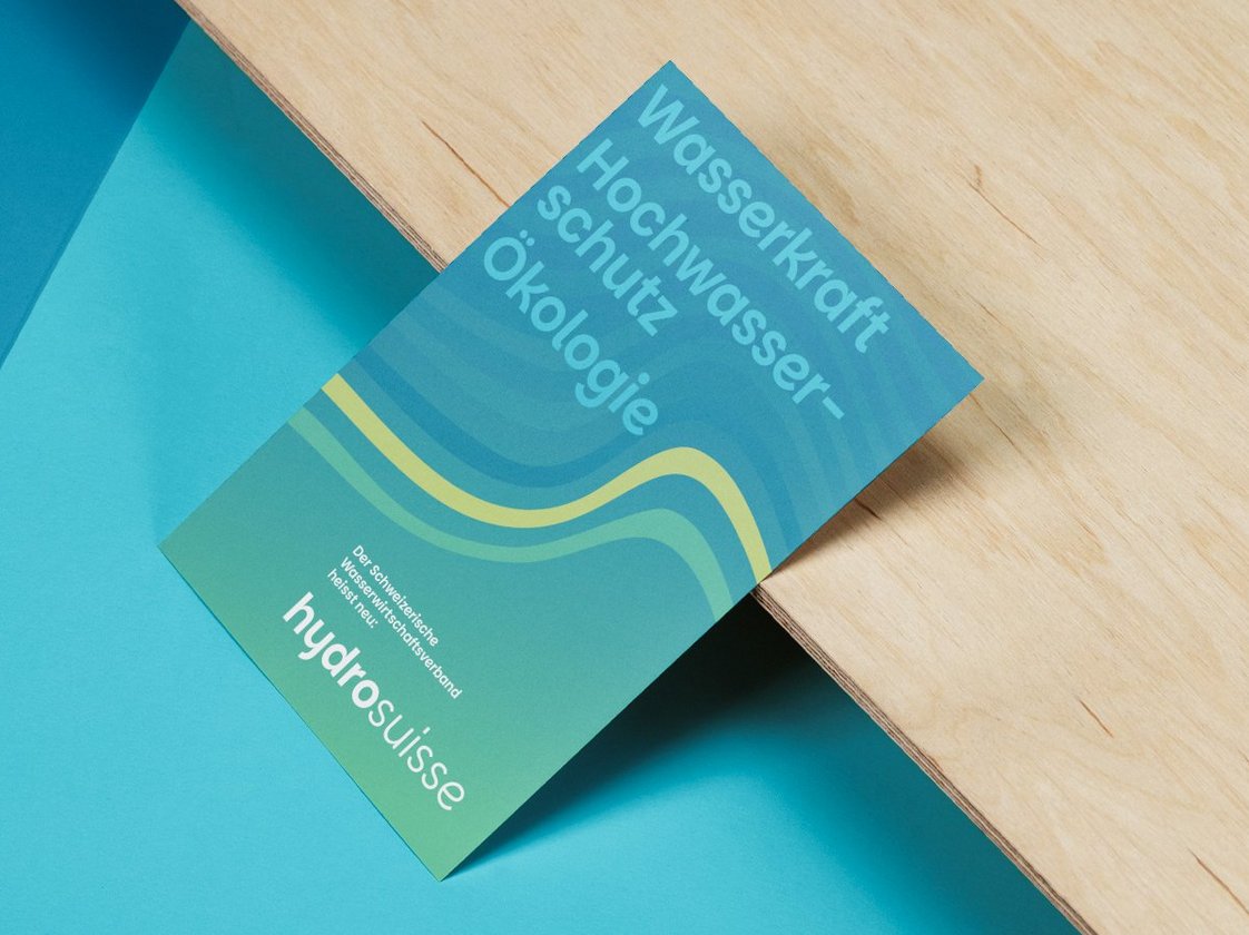 A5-Karte zum Namenswechsel auf hydrosuisse mit Wellenlinien im Corporate Design und den Themen Wasserkraft, Hochwasserschutz, Ökologie.